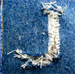 Lettre J formée par une déchirure sur un tissu en jean